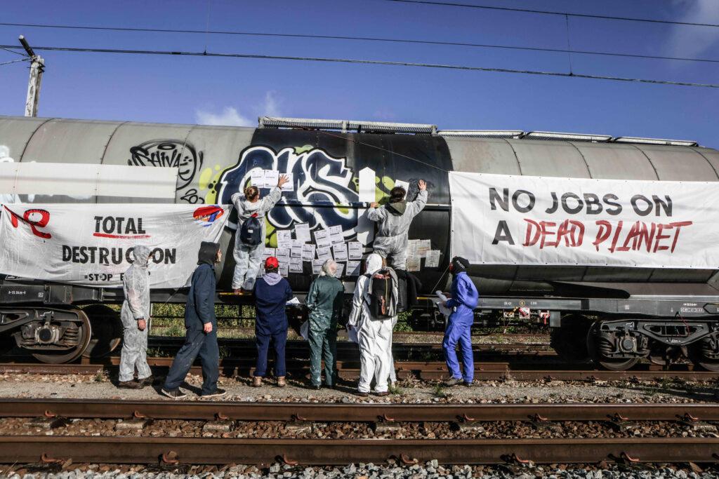 Activisten hangen een banner op een trein waarop staat "No jobs on a dead planet"