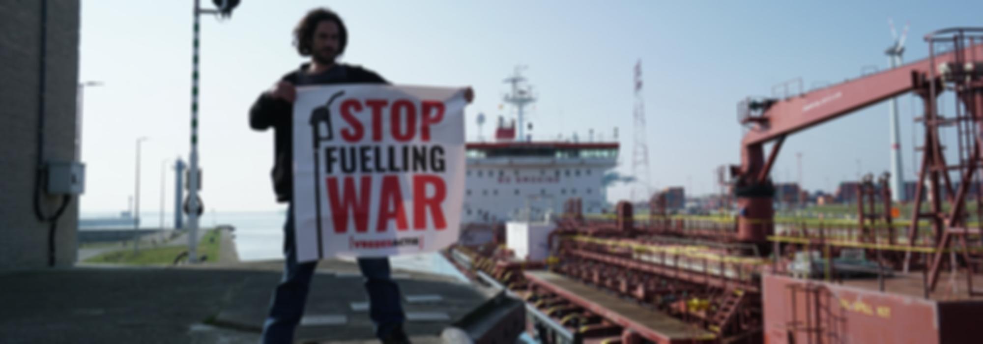 activist naast Russische tanker met spandoek waar Stop Fuelling War op staat