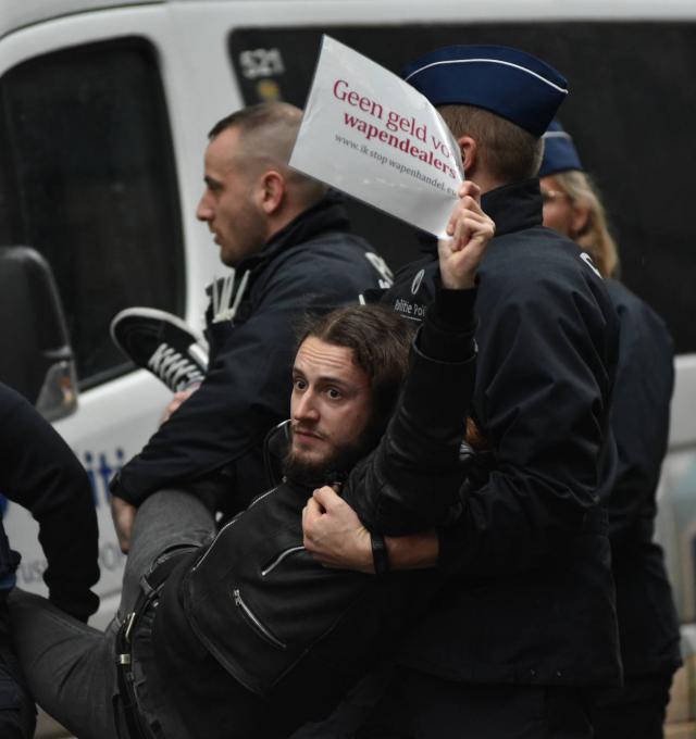 actievoerder wordt weggedragen door politie bij actie aan EDA conferentie