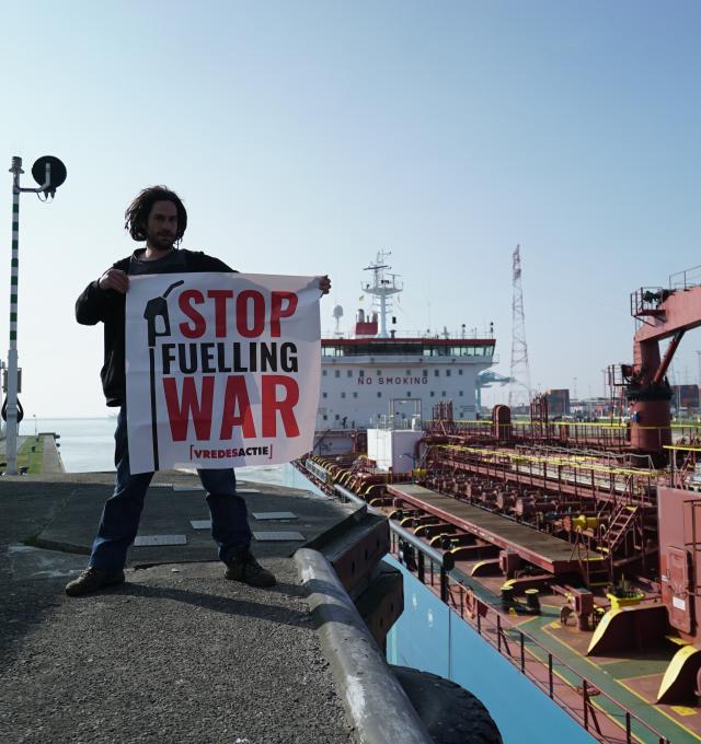 activist naast Russische tanker met spandoek waar Stop Fuelling War op staat