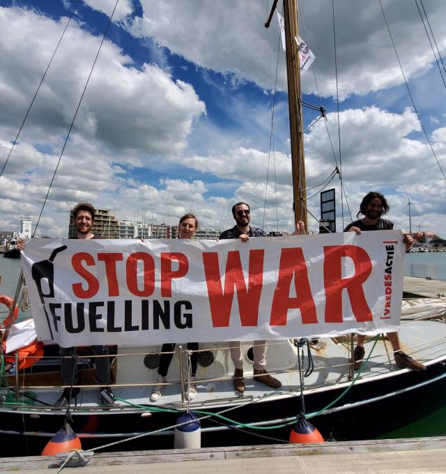 activisten op boot met spandoek Stop Fuelling War